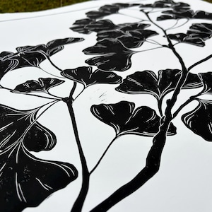a close up of the print, showing the detail of the leaves. the leaves are black with thin white lines to show veins and texture. the branch is knobby in places and looks realistic
