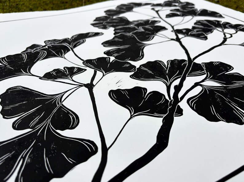 a close up of the print, showing the detail of the leaves. the leaves are black with thin white lines to show veins and texture. the branch is knobby in places and looks realistic