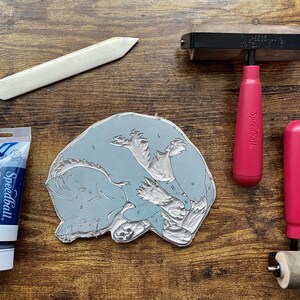The linoleum block, ink, and rollers used to make this print. The block is a reverse image of the print.
