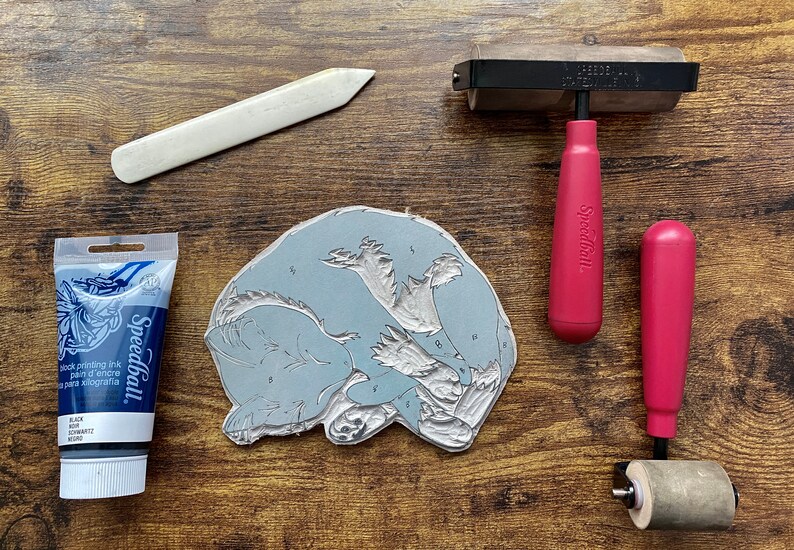 The linoleum block, ink, and rollers used to make this print. The block is a reverse image of the print.