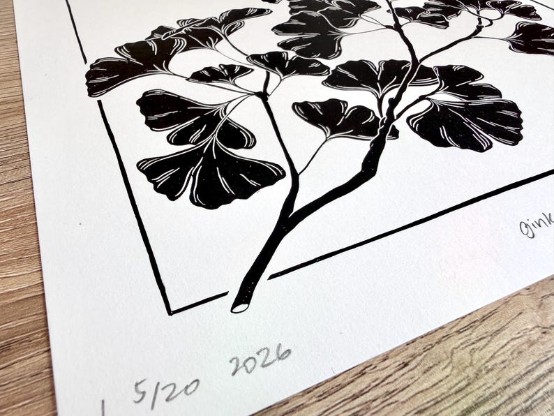 closeup of the lower left corner with the edition and year of the print written in pencil. there is a thin black border around the print with an inch of space between the border and the print edge all the way around. the branch overlaps in front of the border in four places