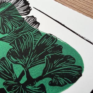a close-up of the print, showing the detail of the leaves. the leaves are black with thin white lines to show veins and texture. the green blob behind the black ink doesnt show through the black but adds dimension.