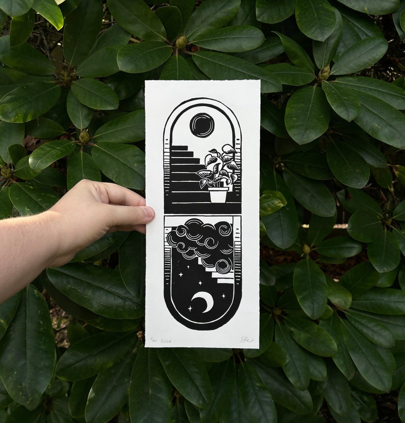Black and white linocut print of two arched doorways. Top arch has black staircase and sun on white sky, a leafy potted plant on bottom stair. The bottom arch is upside down, white staircase and moon on black sky. A cloud hides part of the staircase.