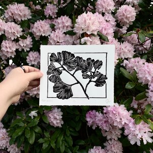 The same print held in front of pink rhododendron flowers