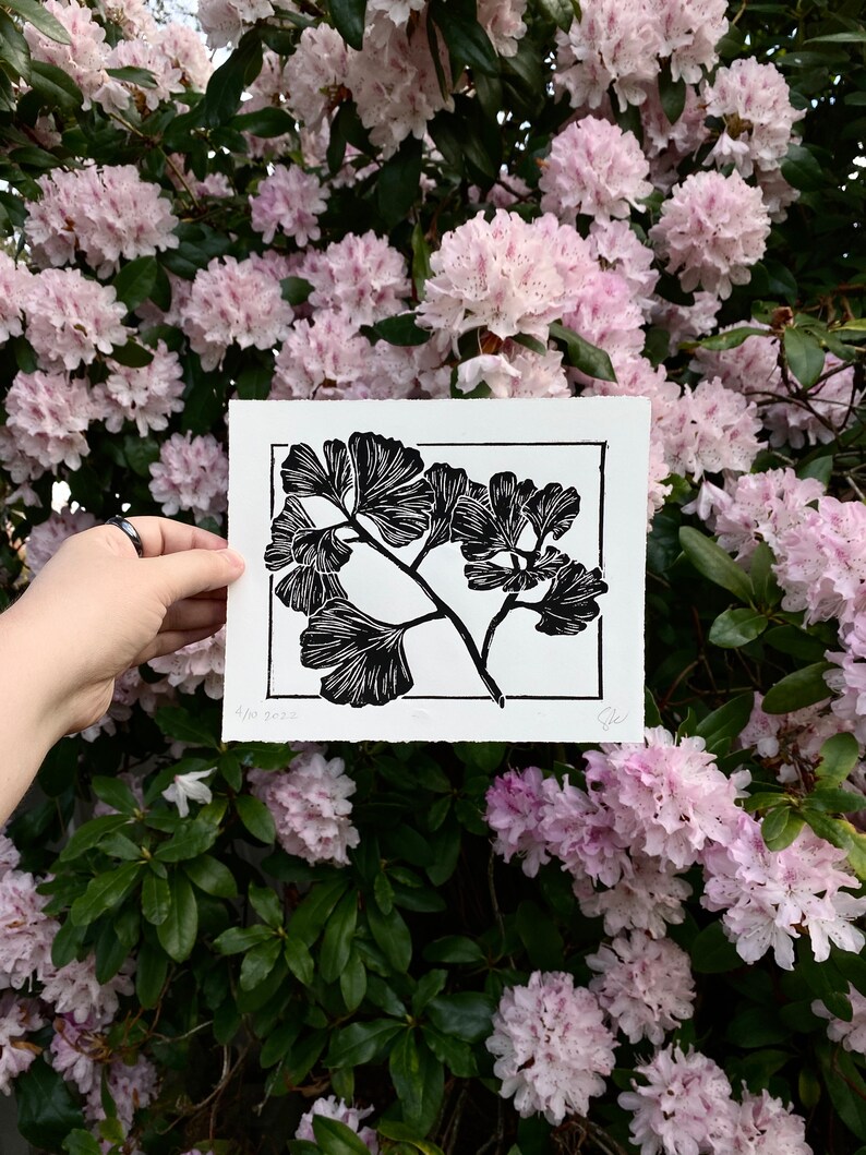 The same print held in front of pink rhododendron flowers