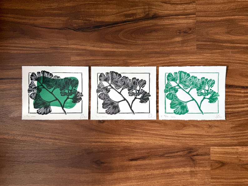 the print next two two other versions. one of the other prints is the black ginkgo image without the green blob, and the other is the ginkgo image printed in the same green color as the blob.