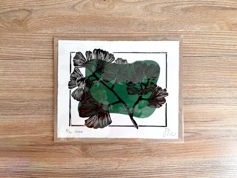 The print packaged in a clear plastic sleeve with a sheet of cardboard behind it.
