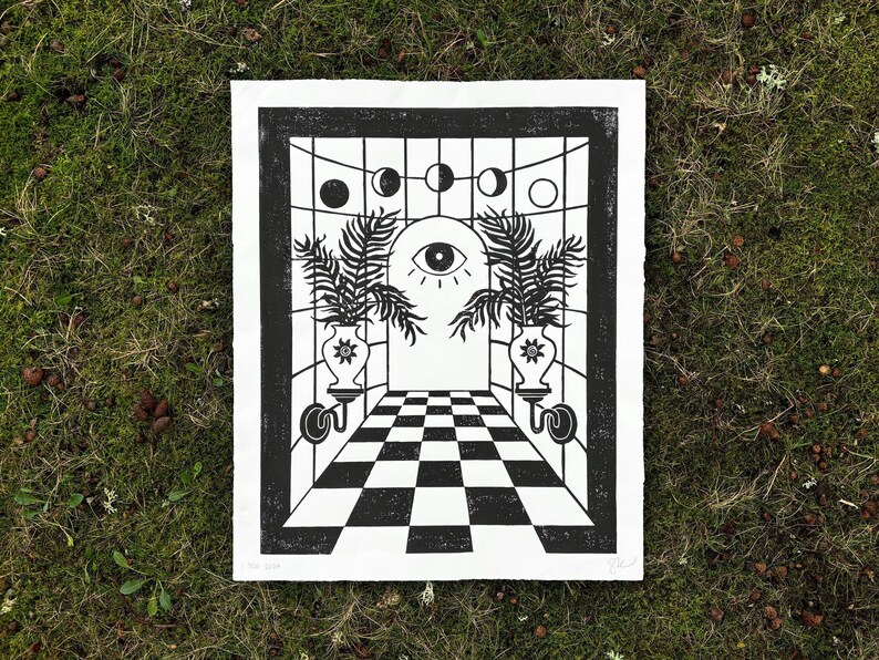 a large portrait oriented linocut print in black ink on white paper. in the center is an arched doorway with a large open eye in the center staring right at you. 2 vases with suns on them on either side of the door, each with three large palm leaves
