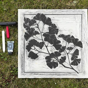 The linoleum block, ink, and rollers used to make this print. The block is a reverse image of the print.