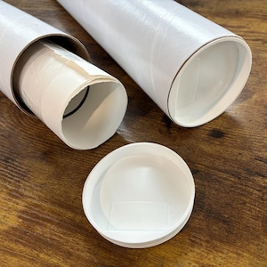 the print packaged for shipping. it is rolled into a tube and put inside a plastic sleeve. the plastic sleeved print is sticking out of a 3 inch mailing tube made of thick sturdy cardboard. another tube next to it is sealed with a plastic lid