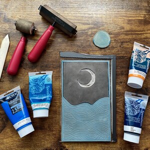 The linoleum block, ink, and rollers used to make this print. The block is a reverse image of the print.