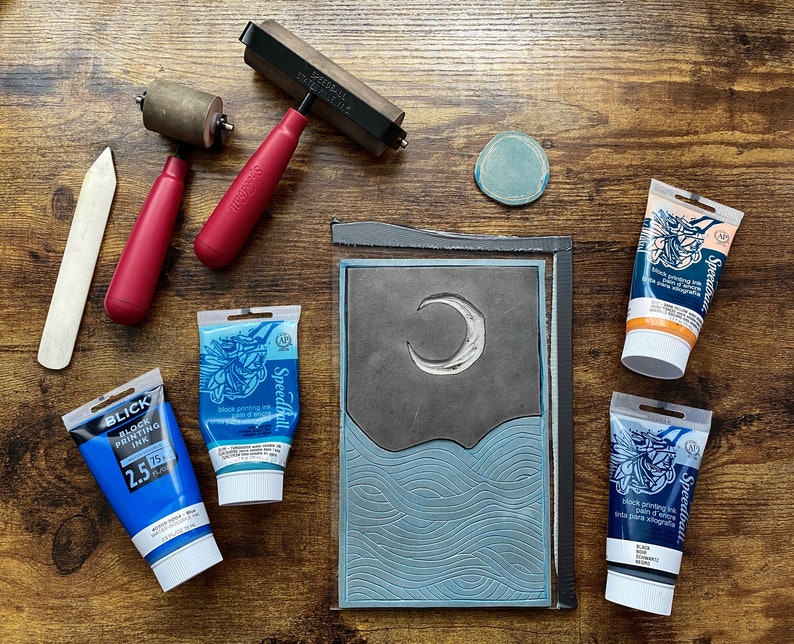 The linoleum block, ink, and rollers used to make this print. The block is a reverse image of the print.