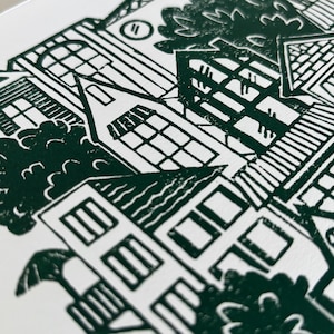 A closeup of the top left corner of the print, showing finely carved details of the houses’ roofs, walls, and windows. Each house has different details, like a brick roof, round window, striped window awning, and a power line connecting two houses