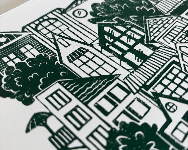 A closeup of the top left corner of the print, showing finely carved details of the houses’ roofs, walls, and windows. Each house has different details, like a brick roof, round window, striped window awning, and a power line connecting two houses
