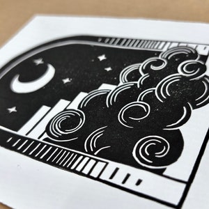 Angled close-up of the nighttime archway print. Five small pointy stars sit around the moon, which is in the center of the sky under the arch. The cloud has curling white lines on it, like those on the sun.