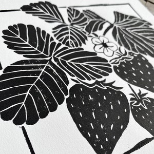 a close-up of the print, showing a few leaves and a strawberry. the leaves are black with white veins and the strawberries are black with white seeds.