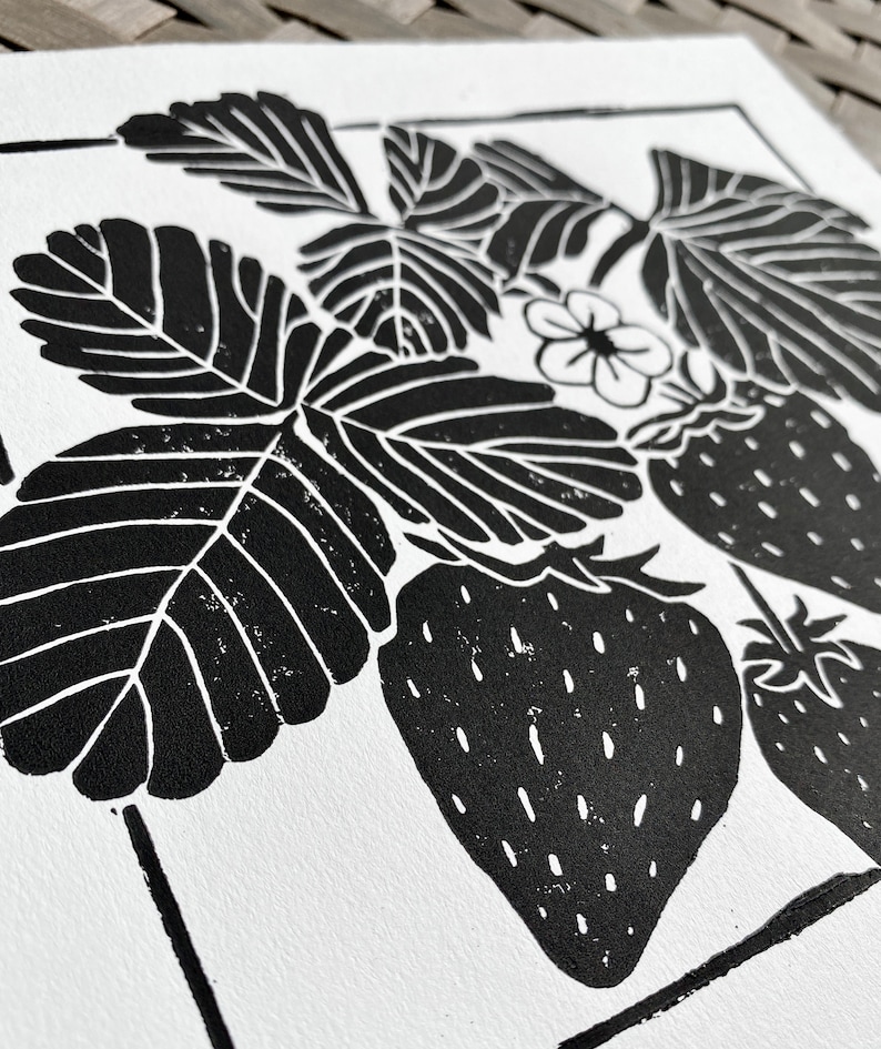 a close-up of the print, showing a few leaves and a strawberry. the leaves are black with white veins and the strawberries are black with white seeds.