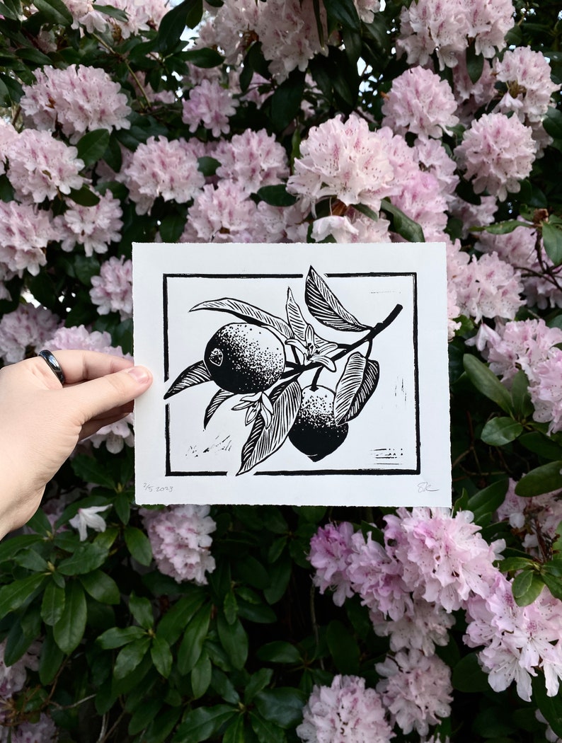 The same print held in front of pink rhododendron flowers