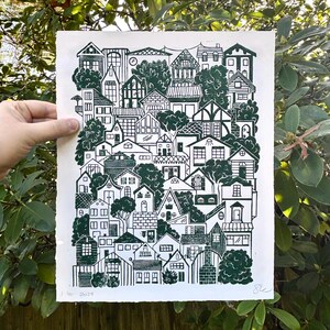 The same print held in front of a green rhododendron bush