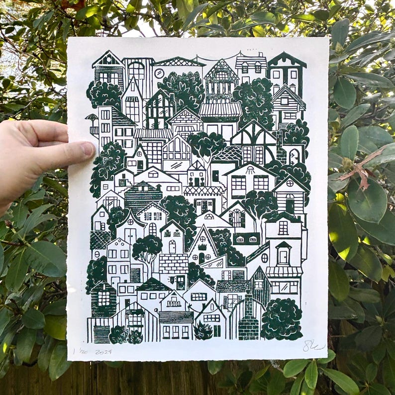 The same print held in front of a green rhododendron bush