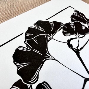 a close up of the print, showing the detail of the leaves. the leaves are black with thin white lines to show veins and texture. the branch is knobby in places and looks realistic.