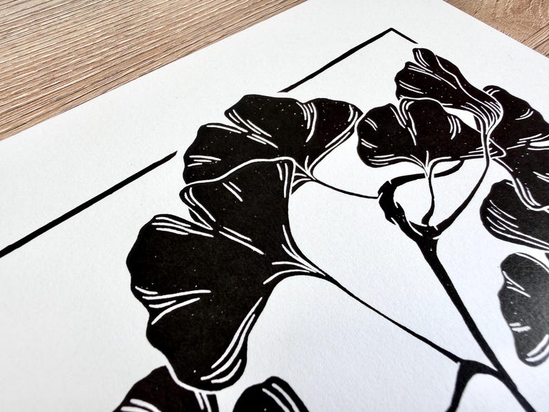 a close up of the print, showing the detail of the leaves. the leaves are black with thin white lines to show veins and texture. the branch is knobby in places and looks realistic.