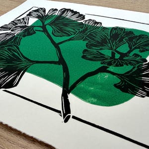 a closeup of the print from a low angle. the green blob behind the black ginkgo is visibly textured, giving the print a handmade feel.
