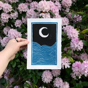 The same print held in front of pink rhododendron leaves.