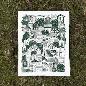 a large linocut print with dark green ink on white paper. it shows roughly fifty houses in a variety of architecture styles stacked on top of each other as though sitting on a hillside. trees and bushes poke out from between the houses.