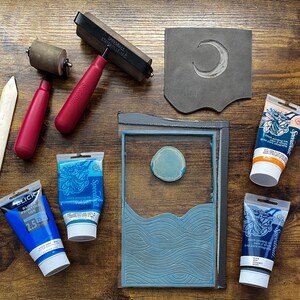 The linoleum block, ink, and rollers used to make this print. The block is a reverse image of the print.