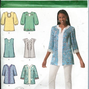 May include: Simplicity pattern 2448 for women's tops and tunics. The pattern includes various styles, such as a tunic with a V-neck and three-quarter sleeves. The image shows a woman wearing a blue and white tunic and white pants.