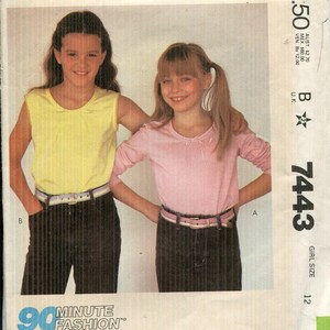 May include: McCall's sewing pattern envelope showing two girls in tops and trousers. The envelope reads "McCall's 7443 GIRL SIZE 12" and "90 MINUTE FASHION". The pattern is for stretch knit fabrics.
