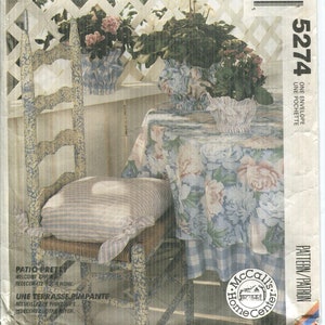 May include: McCall's Crafts pattern envelope featuring a patio scene. The image shows a chair with a striped cushion, a floral tablecloth, and potted plants. The text includes "Patio Pretty" and "Welcome Spring".