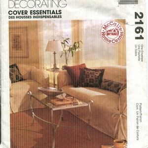 May include: A McCall's Home Decorating pattern envelope. The image shows a living room scene with a sofa, pillows, a glass-topped coffee table, and a lamp. The text on the envelope reads "Cover Essentials".