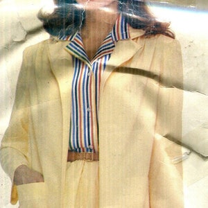 May include: A vintage pale yellow skirt suit with a matching jacket and skirt. The jacket has a notched collar and pockets. A striped blouse in red, blue, and yellow is visible beneath the jacket. The outfit is completed with a brown belt and red bracelets.