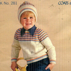May include: A cream-colored knitted sweater and matching beanie with horizontal orange and blue stripes. The sweater features a ribbed texture and a dark blue collared shirt underneath. The text K No. 281 and COATS are visible at the top.