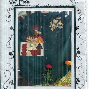 May include: A pattern titled "Mulberry Tree" with the text "Gardening Pleasures" and the code "MT-26". The image features a dark green shirt adorned with fabric appliques of birdhouses, flowers, and a beehive. Decorative floral elements frame the image.