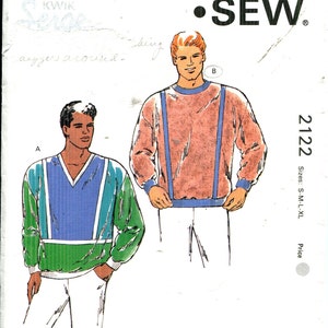 Könnte beinhalten: Kwik Sew Schnittmuster 2122 mit Abbildungen von zwei langärmeligen Pullovern. Einer hat einen V-Ausschnitt mit blauen und grünen Details, der andere blaue Hosenträger-Details. Größen: S-M-L-XL.