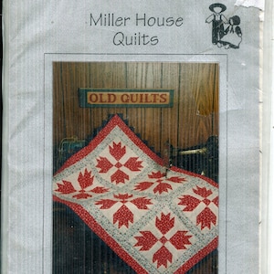 May include: A baby quilt package with a Bears Paw pattern in red and white. The finished quilt size is approximately 91cm x 112cm. The package is labelled "Miller House Quilts" and includes the text "Old Quilts".