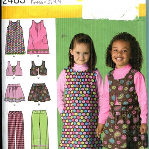 Può includere: Cartamodello Simplicity 2483 taglia A per abbigliamento da bambino che include vestito, gilet, gonna e pantaloni. La busta mostra illustrazioni di questi capi in vari motivi e colori, insieme a fotografie di due bambini che indossano gli abiti.