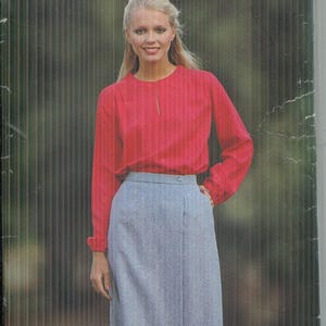 Puede incluir: Una caja de patrones de costura vintage con el texto "See & Sew" y "by Butterick". La imagen presenta a una mujer con una blusa roja de manga larga y una falda azul claro. La talla del patrón es B.