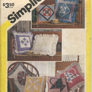 May include: A Simplicity 6146 sewing pattern envelope featuring illustrations of various square decorative pillows with ruffles, lace trim, and patchwork designs including star, basket, and floral motifs in assorted colors like red, blue, purple, and yellow.