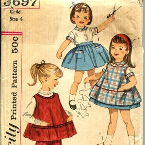 May include: Vintage Simplicity sewing pattern for a child's size 4. The illustration shows three children in different outfits: a blue skirt and top, a plaid dress, and a red outfit. The pattern number is 3697.