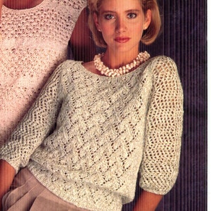 May include: A woman wearing a light green knitted sweater with a textured diamond pattern and three-quarter sleeves. The sweater has a round neckline and is paired with a pearl necklace and tan pants. The image is from a vintage fashion catalog.