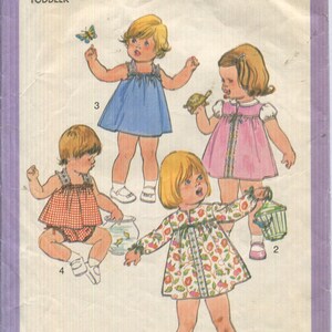 May include: Simplicity 8495 sewing pattern envelope for toddler sizes 1/2 and 1. The cover features illustrations of four children wearing various dresses and a top with bloomers, including floral, solid blue, pink, and red gingham patterns.