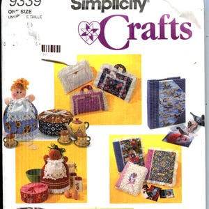 May include: Simplicity Crafts pattern envelope featuring various craft projects. The image showcases a doll, tea set, handbags, a tent, and other items, all with a handmade aesthetic. The envelope has the number 9339 and the price $7.95.