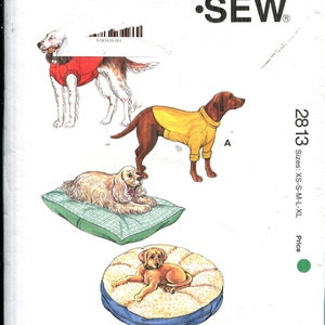 Peut inclure: Un patron de couture Kwik Sew, numéro 2813, avec des illustrations de chiens portant des vêtements et sur des lits. Tailles : XS à XL. Le texte "KWIK SEW" est visible. Mesures en cm.