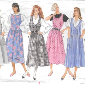 May include: A Butterick Classics sewing pattern envelope featuring illustrations of five different pinafore dress styles. The designs include a solid grey dress, a blue floral print, a black and white houndstooth, a pink polka dot, and a blue striped dress.