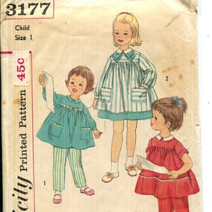 May include: Vintage Simplicity pattern envelope showing illustrations of children's clothing. The designs include a teal dress and trousers, a striped dress, and a red dress and trousers. The envelope is marked "Child Size 1".
