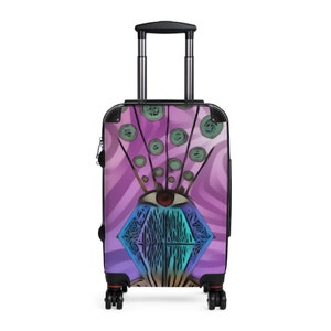May include: A purple and blue patterned suitcase with a diamond-shaped design and a single eye in the center. The suitcase has a black handle and wheels.